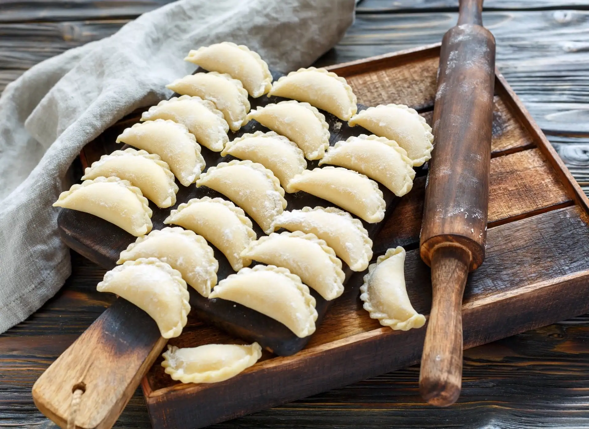 Pierogi i wałek na desce do krojenia